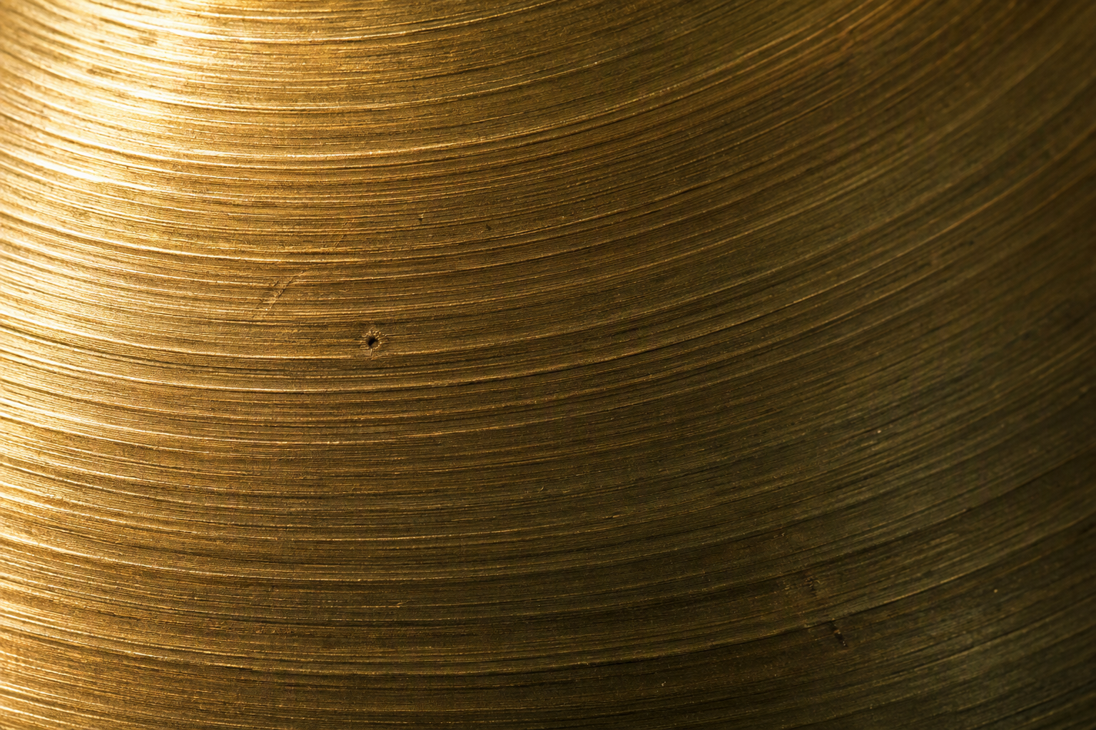 Macro of raw lathe-turned CuSn22 bell bronze, fine concentric turning rings catching the light